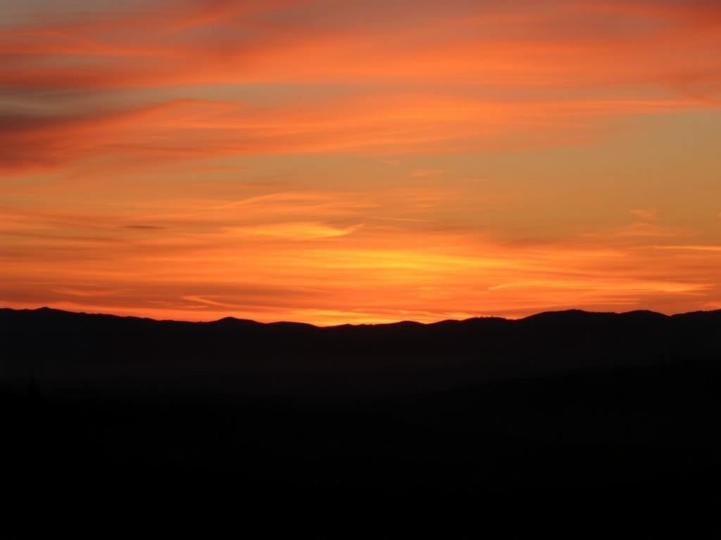 Kamloops sunset over hills with warm orange sky and silhouettes of landscape