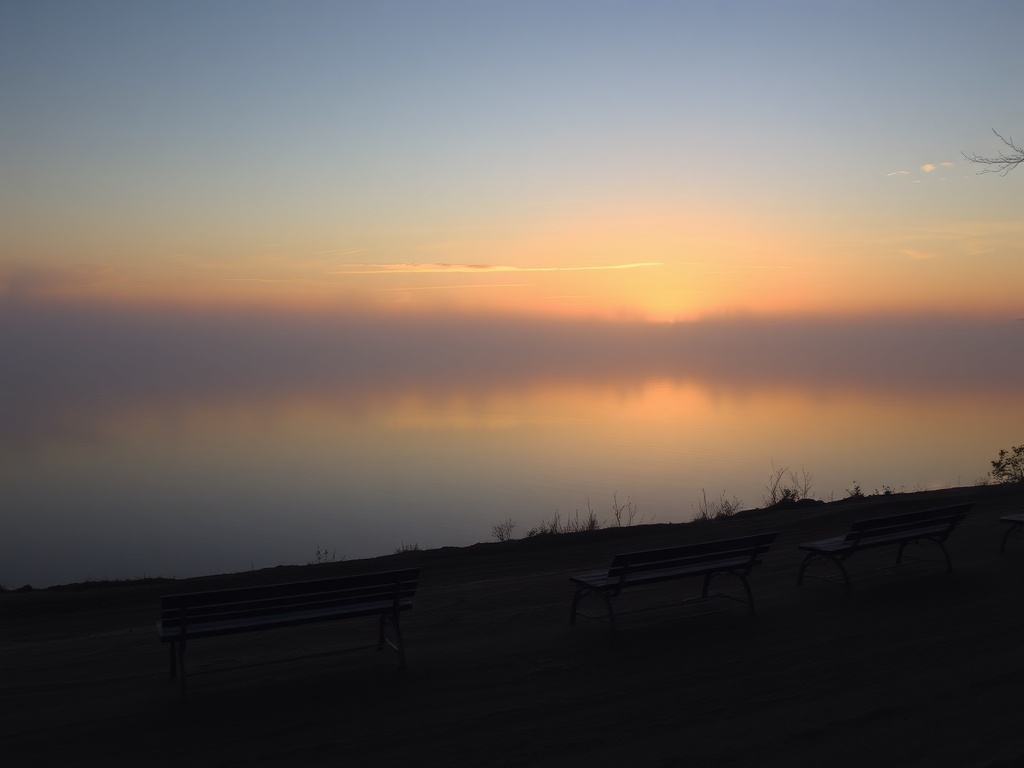 quiet sunrise over Lake Temiskaming with mist, still water, and empty shoreline benches in soft golden light